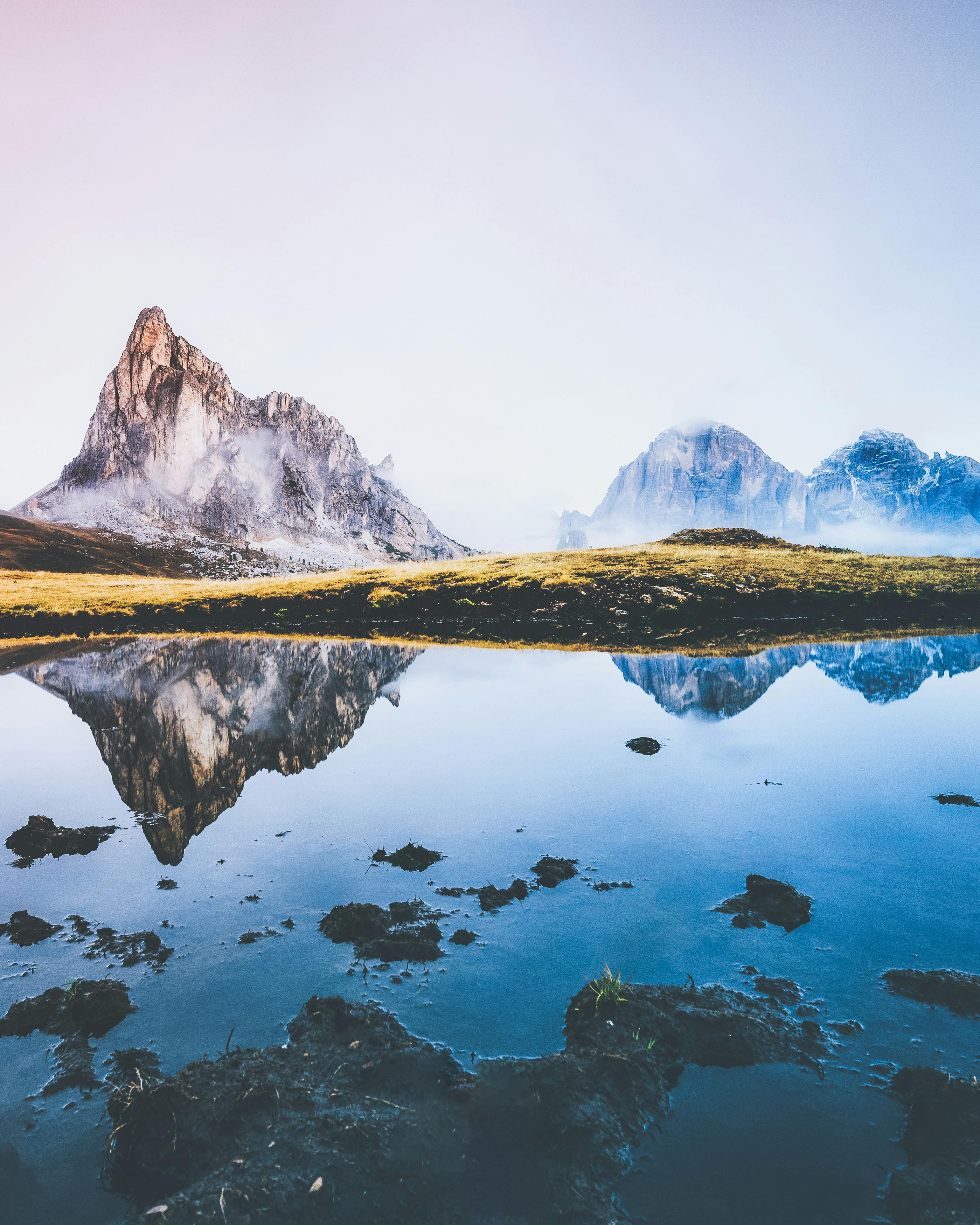 The mountain peaks are reflected in the calm lake water, creating a peaceful natural landscape. - free wallpaper image