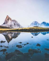 The mountain peaks are reflected in the calm lake water, creating a peaceful natural landscape. - free wallpaper image