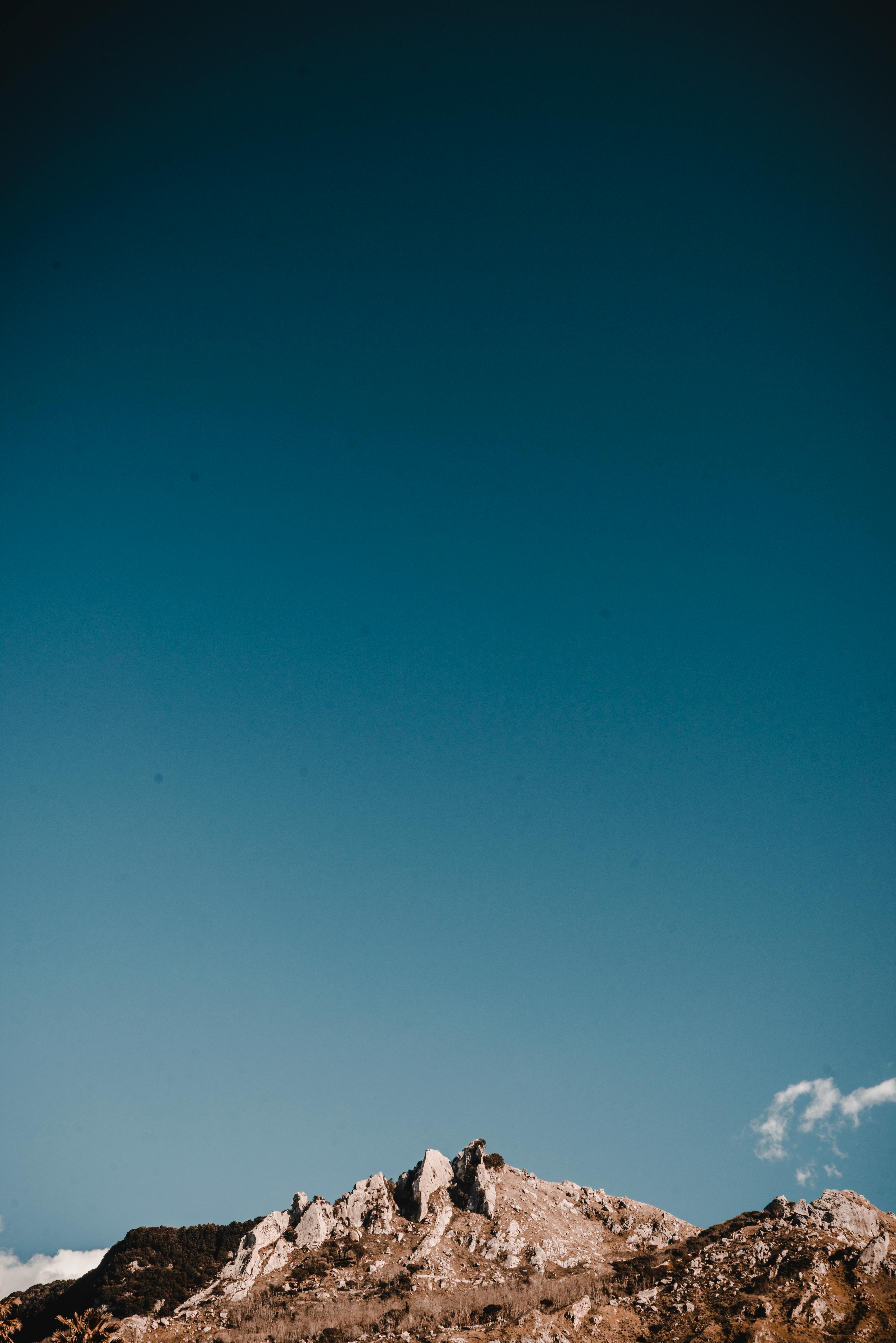 The mountain top looks particularly magnificent against the backdrop of blue sky and white clouds. - free wallpaper image