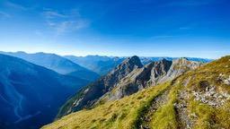 A panoramic view from the top of a mountain, with rolling hills in the distance and a winding path leading to the summit. - free wallpaper image