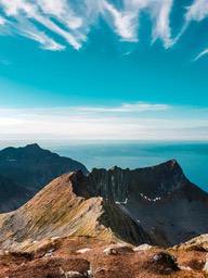 A view from the top of a mountain, the sea in the distance is sparkling, the magnificent scenery of mountains in the near distance. - free wallpaper image