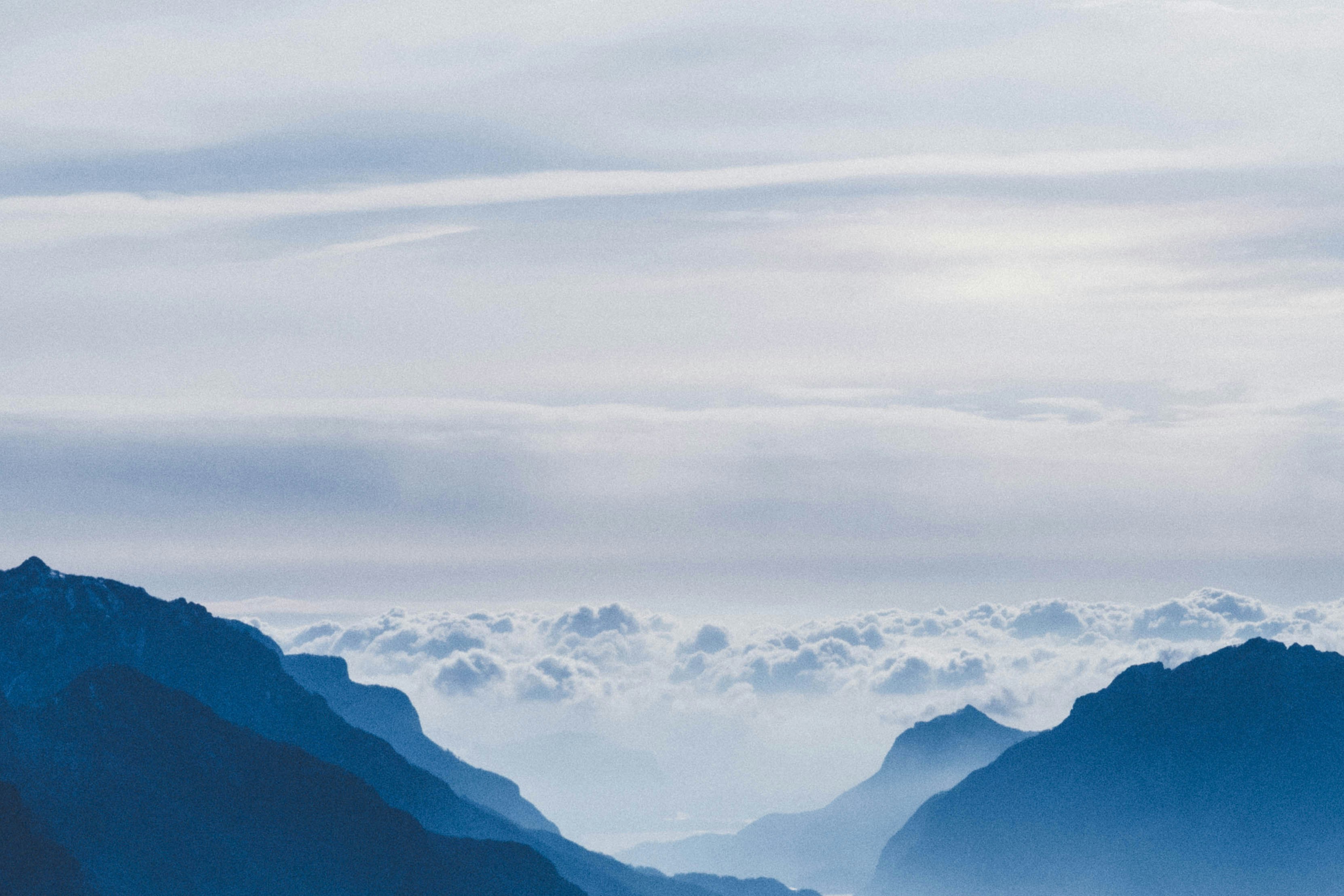 Blue mountains are covered with white clouds, and clouds can be seen vaguely between the mountains, forming a magnificent natural landscape. - free wallpaper image