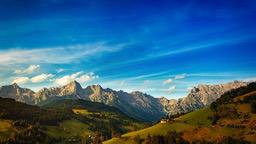 The mountains in the distance stretch as far as the eye can see, the slopes are covered with green vegetation, the sky is blue, and the clouds are drifting. - free wallpaper image