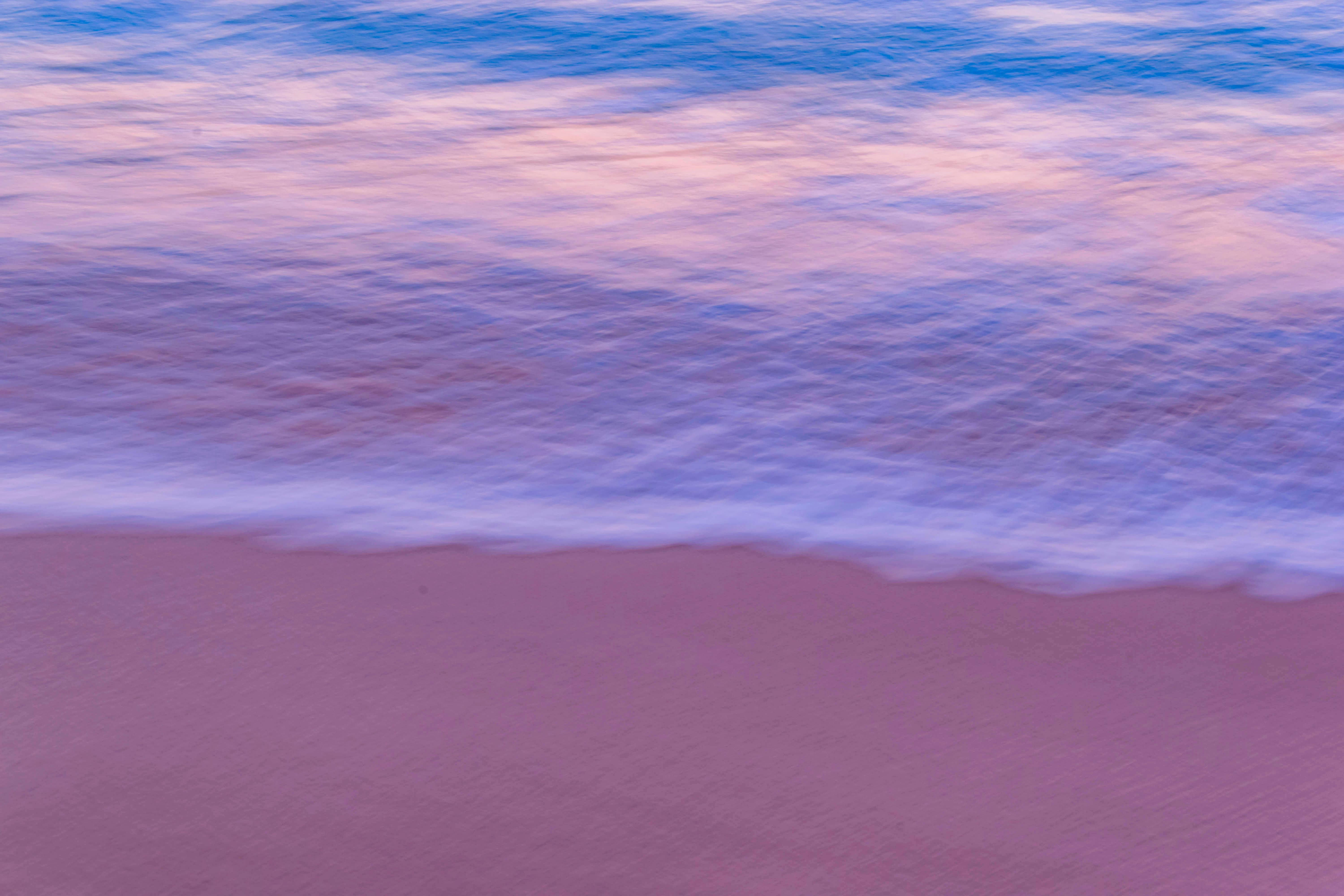 Pink sand beach with blue waves and sky color gradient from blue to pink, it looks like an evening scene. - free wallpaper image