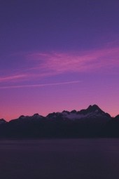 The sky is purple and pink at sunset, with mountains silhouetted in the distance. - free wallpaper image