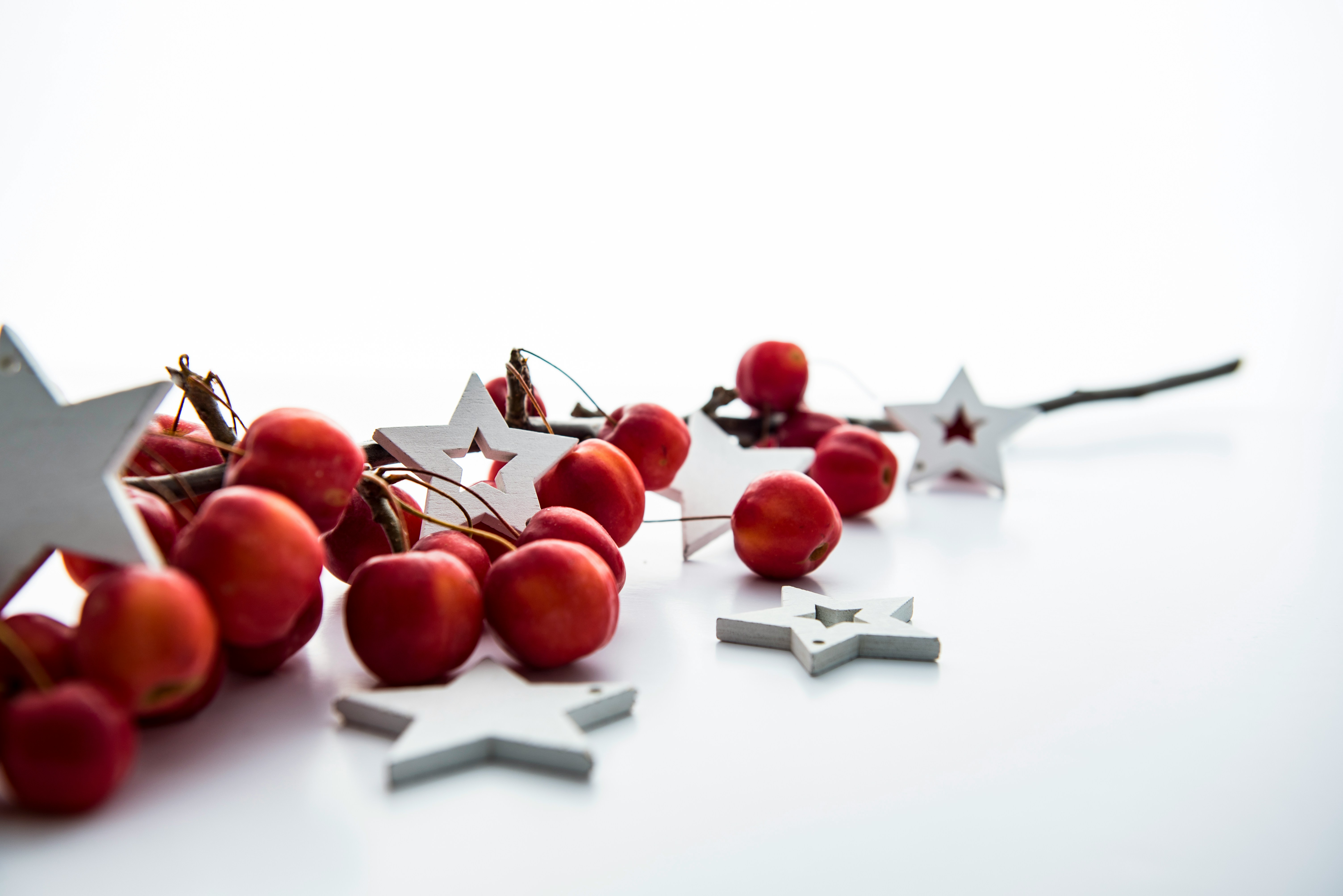 Some red apples and white star-shaped ornaments are placed on a white background. - wallpaper image