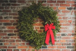 A red Christmas wreath decorates a red brick wall. - wallpaper image