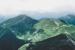 Rolling hills, layer upon layer, green covers the mountains, the distant peaks are shrouded in mist, presenting a peaceful and serene atmosphere. - free wallpaper image