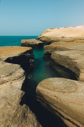 A narrow channel formed between rocky cliffs, the sea forms a clear blue pool here. - free wallpaper image