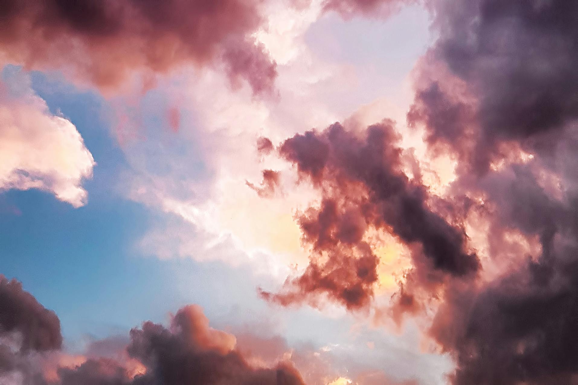 A picture of clouds in the sky, the clouds are a gradient of pink, purple and blue, the sun shines through the clouds, making it particularly beautiful. - free wallpaper image