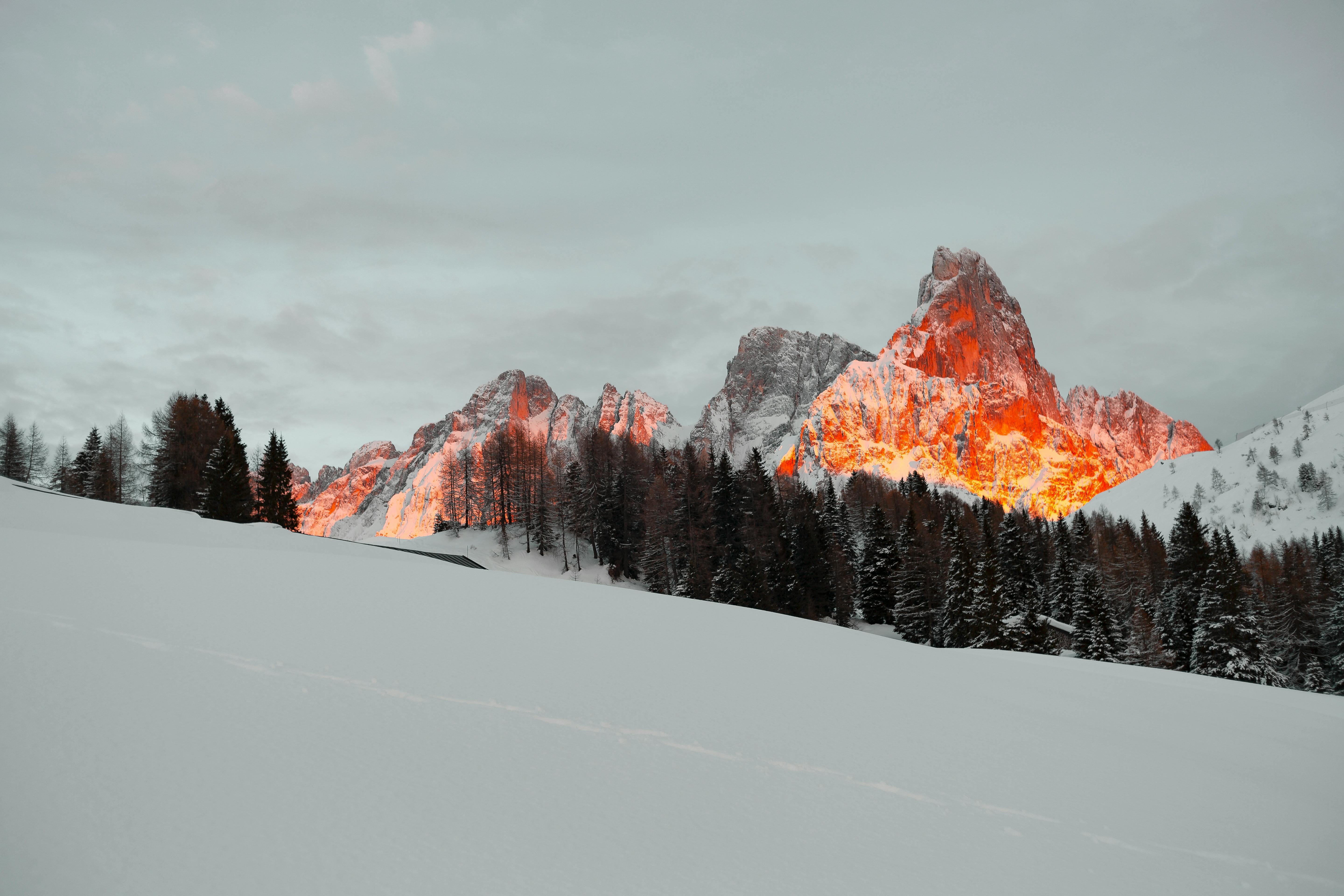 The snow-capped mountains are bathed in the setting sun, the summit is orange-red, and the slopes are covered with white snow. - free wallpaper image