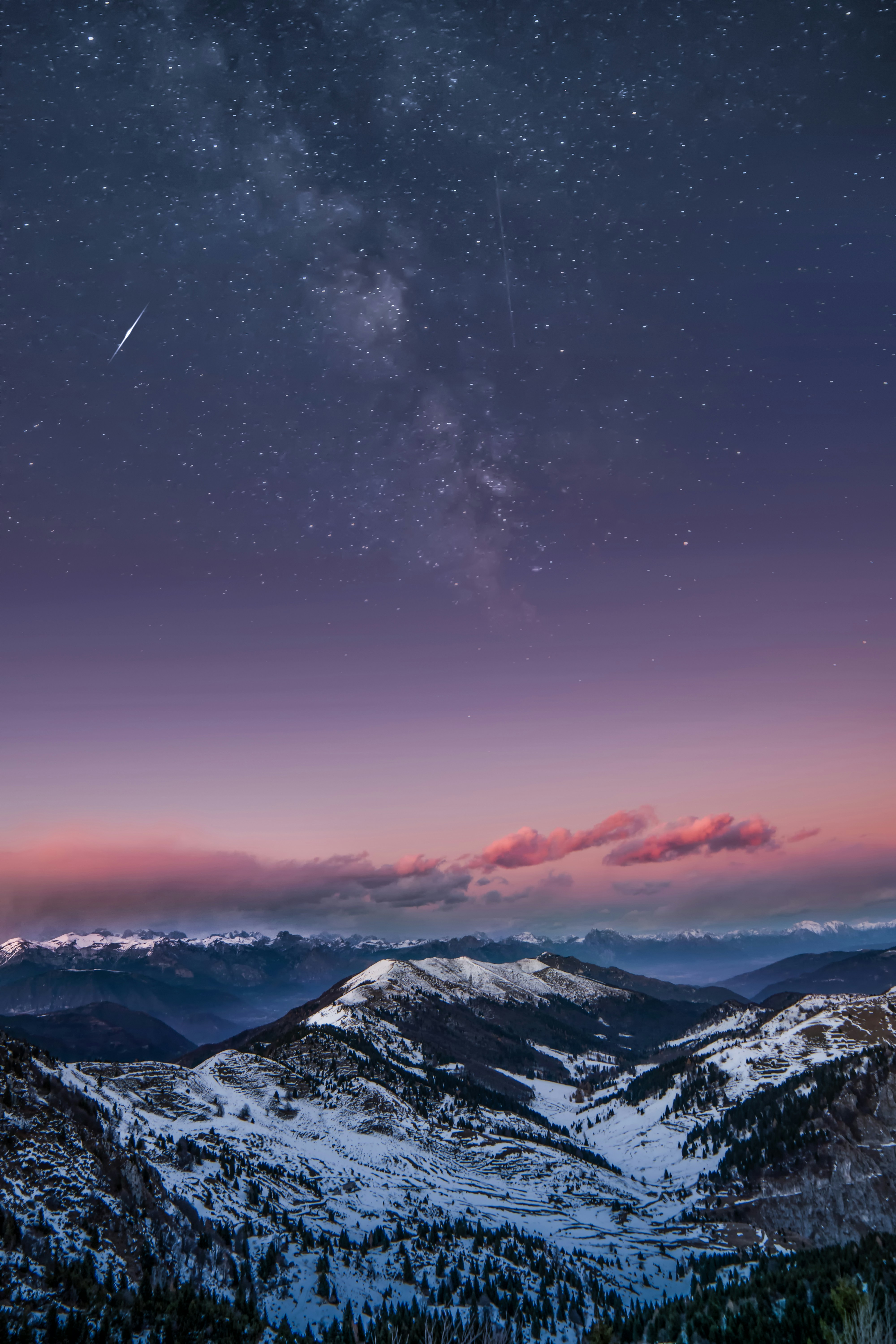 A snowy mountain peak at night, with the Milky Way and a shooting star visible. The peak is covered in snow, with a dense forest at the foot of the mountain. - free wallpaper image