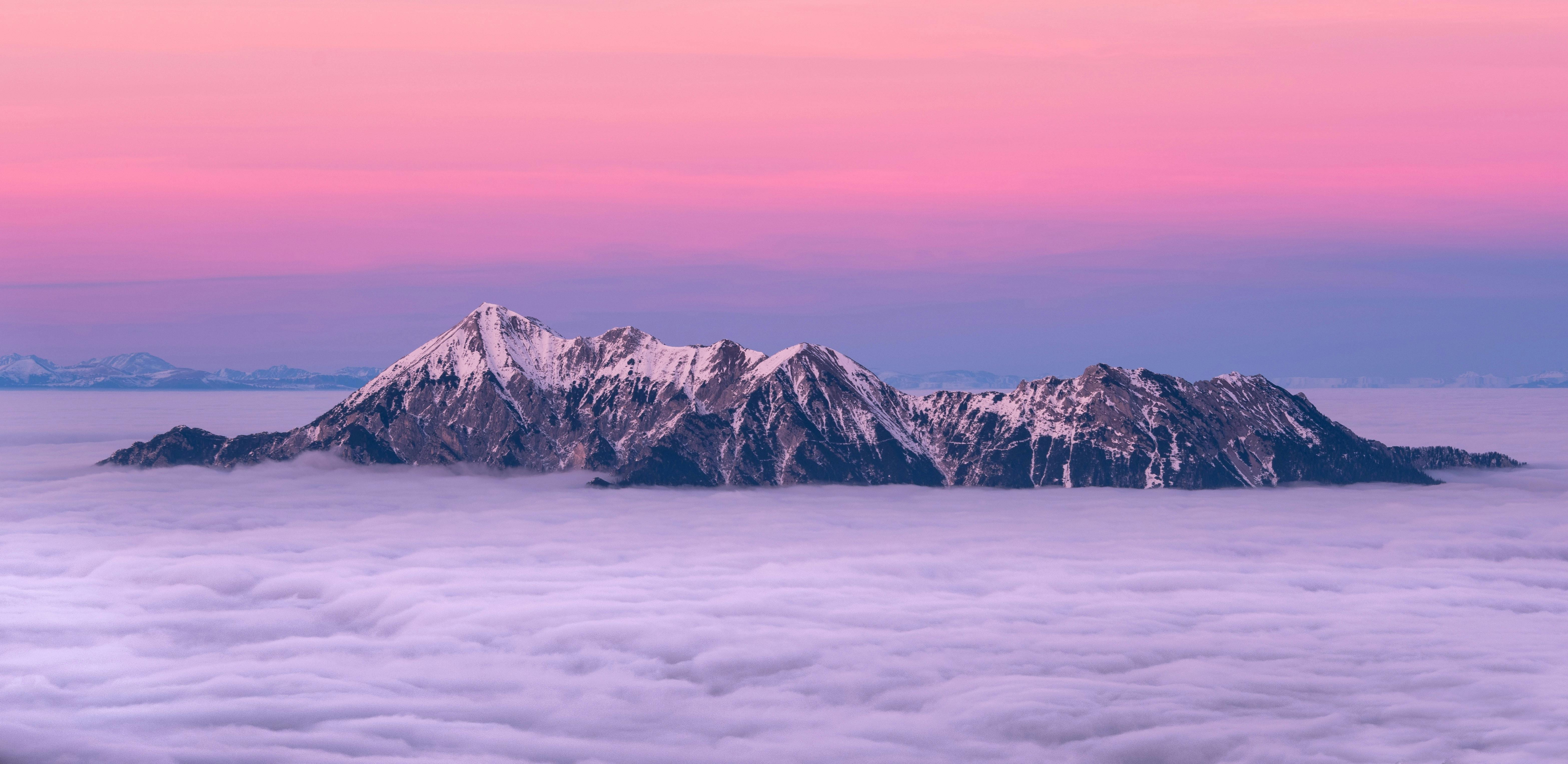 The top of the mountain is covered with white snow, the sea of clouds is surging, the sky is a dreamy pink and purple, and the distant sky is a deep blue. - free wallpaper image