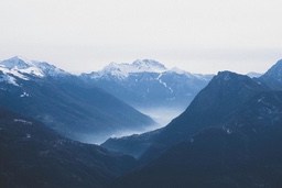 The distant mountains are covered with snow, and the valley is shrouded in mist, creating a peaceful and serene scene. - free wallpaper image