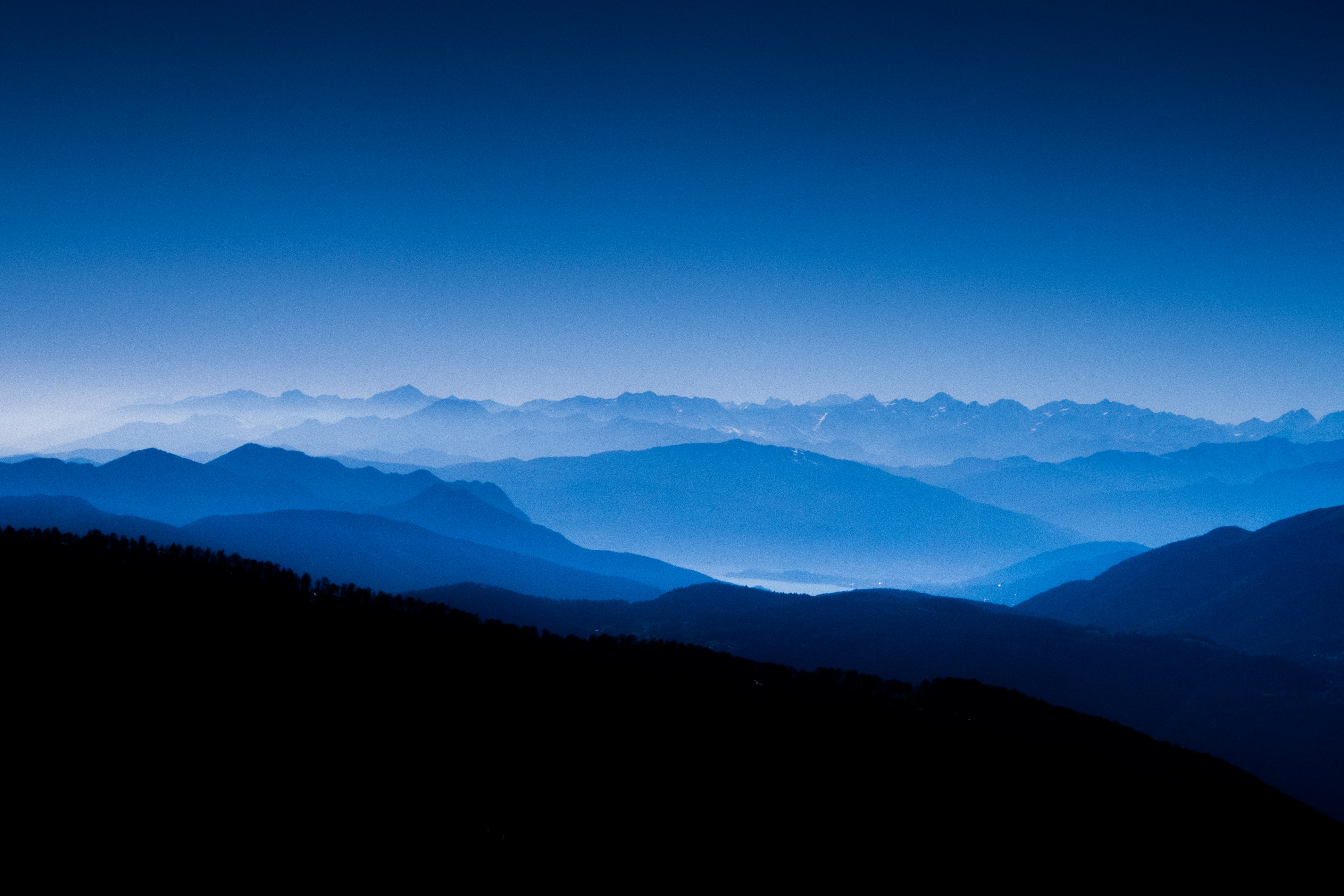 Distant mountains are layered under a blue sky, with snow-capped peaks, the scene is magnificent and beautiful. - free wallpaper image