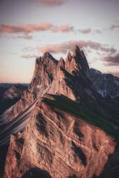 A mountain range under the setting sun, with clouds swirling at the peak, presents a magnificent natural landscape. - free wallpaper image