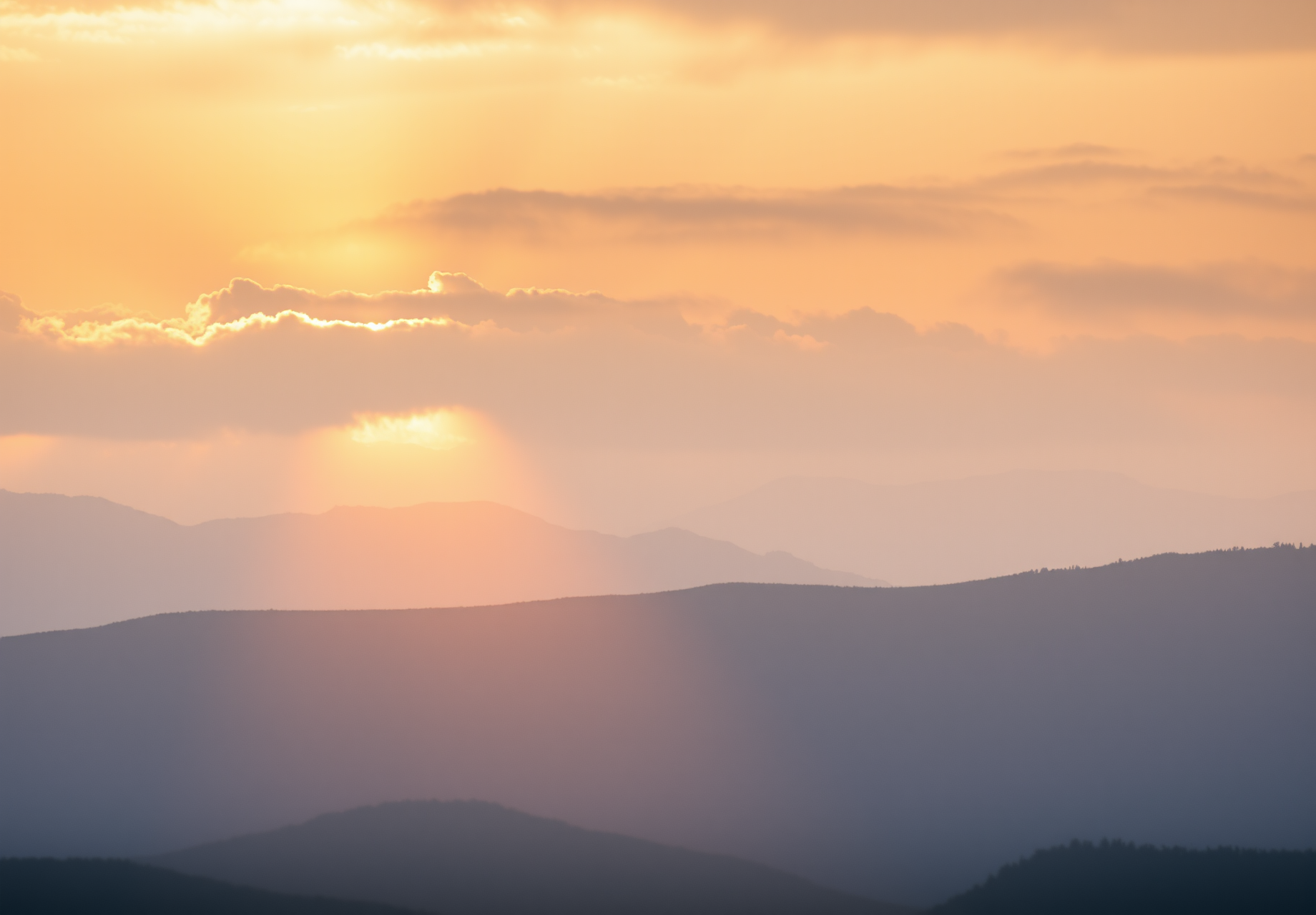 The sunset casts an orange and purple hue on the clouds, with rolling hills and a spectacular view. - wallpaper image