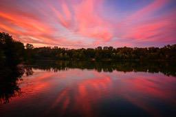 The sky is painted red and pink by the setting sun, reflecting in the calm lake, creating a beautiful scene. - free wallpaper image