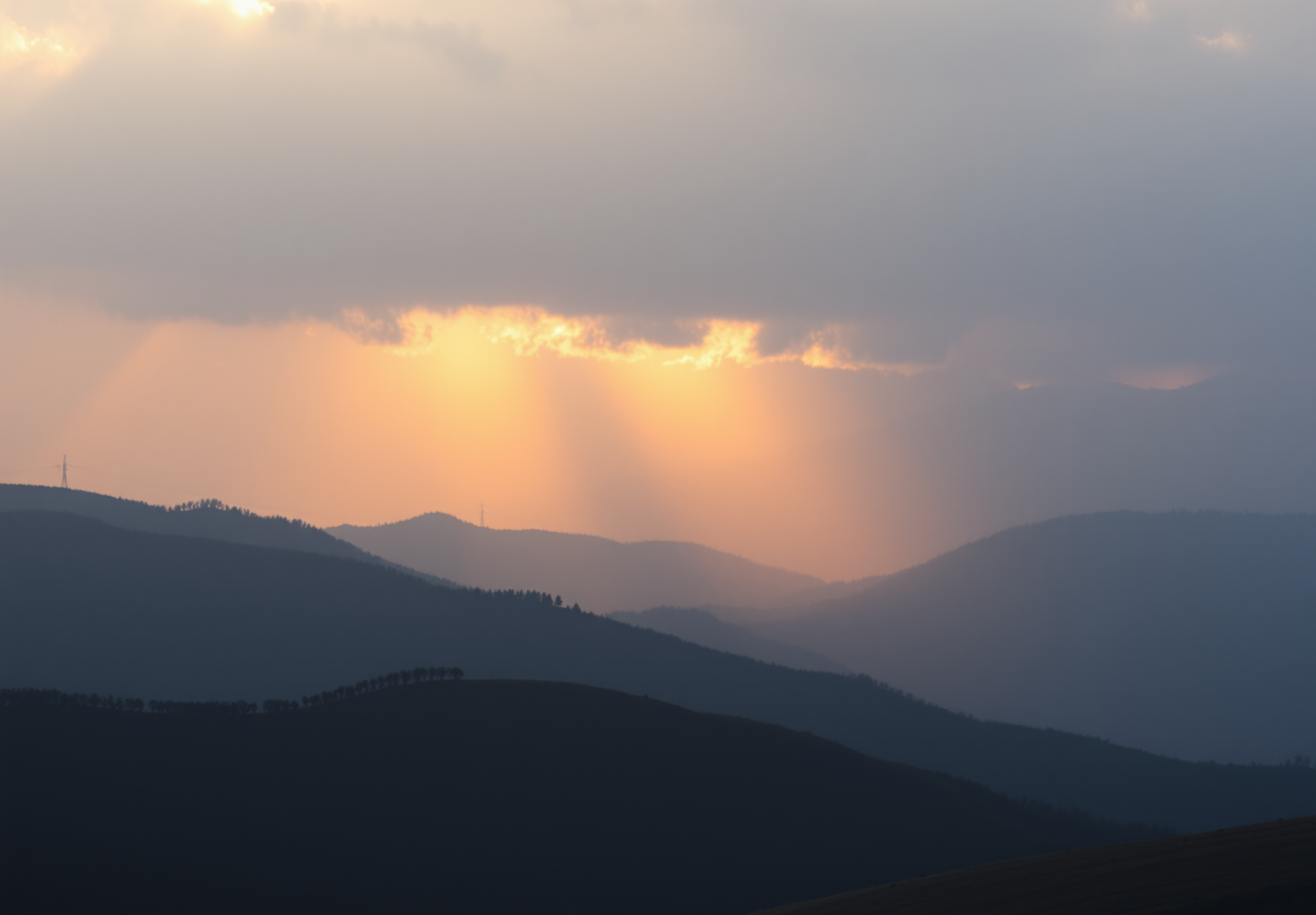 The sun sets in the west, and golden rays of light shine through the clouds, illuminating the distant mountains. - wallpaper image