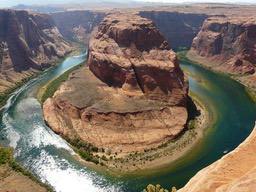 A river winds its way through a red canyon, forming a horseshoe shape, as seen from a high vantage point. The view is breathtaking. - free wallpaper image