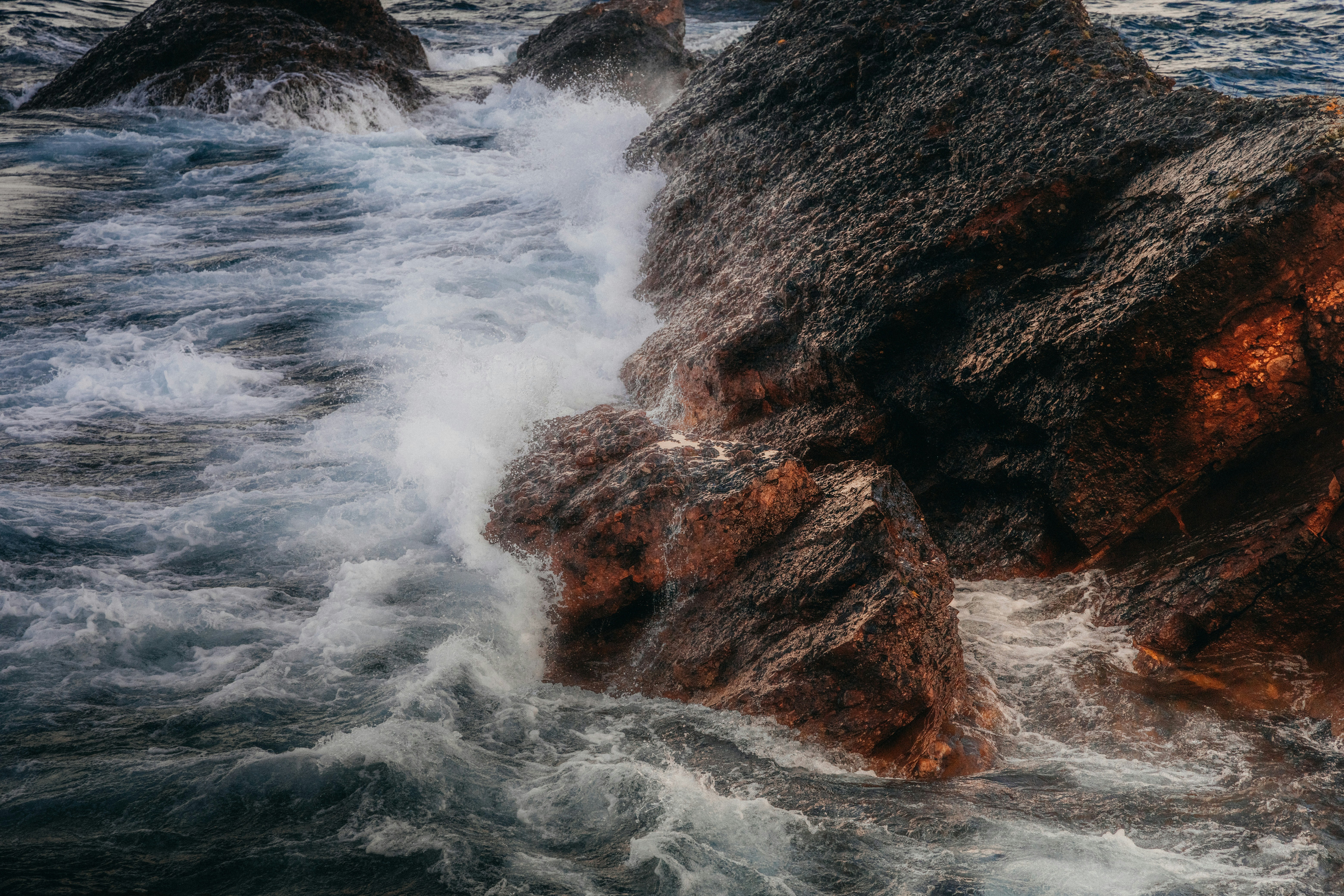 Waves crashing against rocks, forming white foam - free wallpaper image