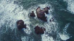 An aerial view of a few rocks standing in the rough sea. - free wallpaper image