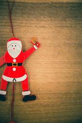 A wooden Santa Claus doll on a wooden background, the doll is wearing a red suit and a white hat, wearing a black hat, looks very festive. - wallpaper image